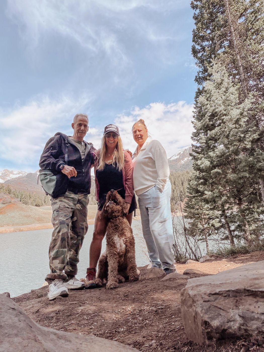 Charles hiking at a mountain lake with his wife, daughter, and the family dog